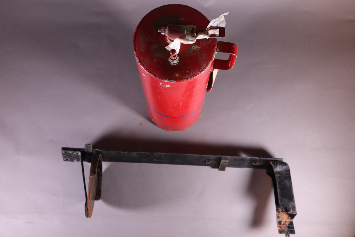 Brannslukningsapparat med veggfeste. Håndtak nesten helt oppe på ene siden.