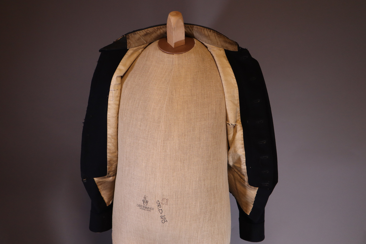 Fangejakke med påsydd lapp med fangenummer og bokstav.