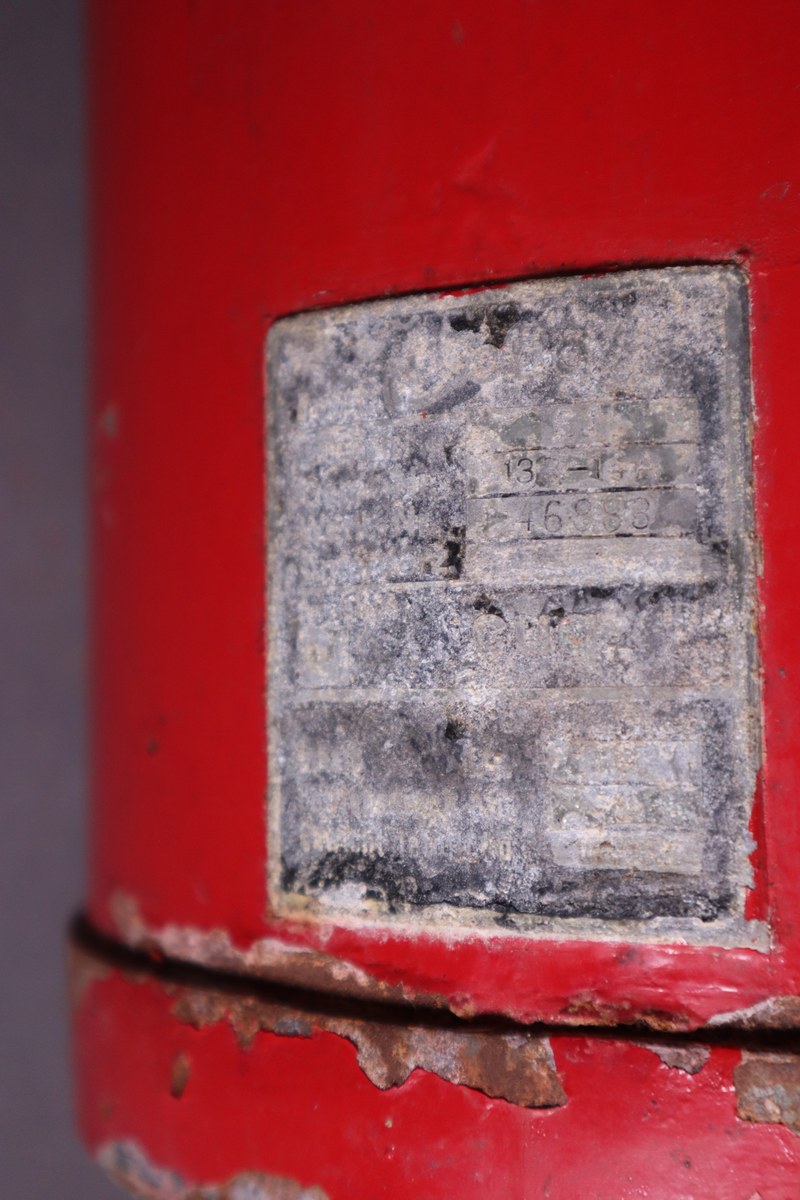 Brannslukningsapparat med veggfeste. Håndtak nesten helt oppe på ene siden.