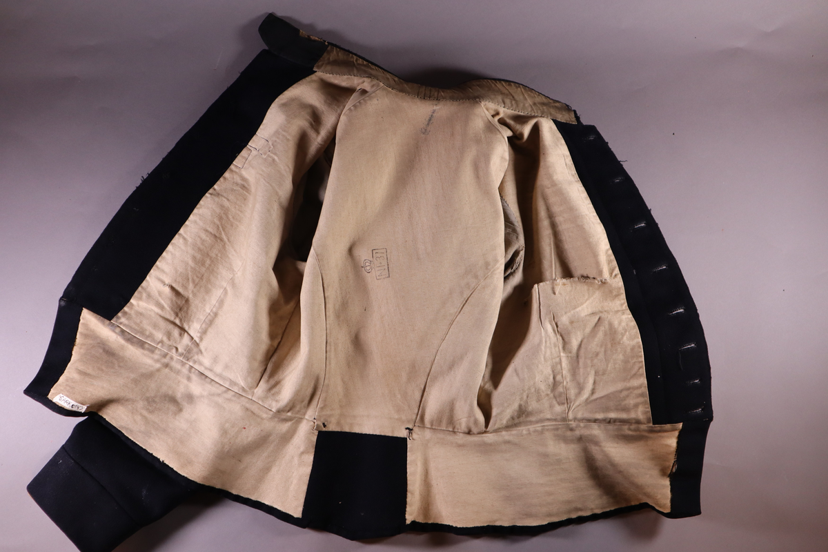 Fangejakke med påsydd lapp med fangenummer og bokstav.