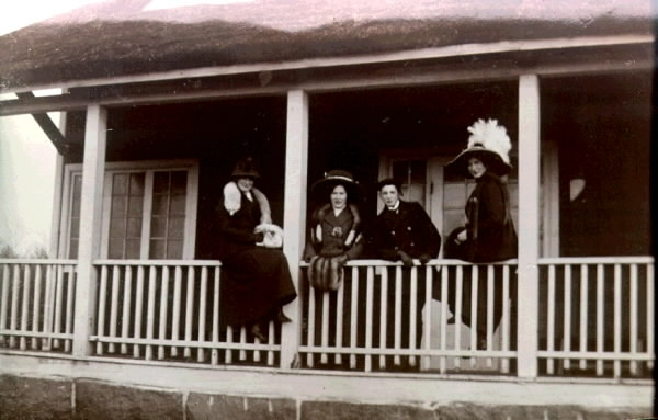 Fyra kvinnor i stora hattar år 1912 vid verandaräcket på Tivedstugan i Påskbergsskogen. (Bilden tillhör samlingen från firma Linda Hanson.)