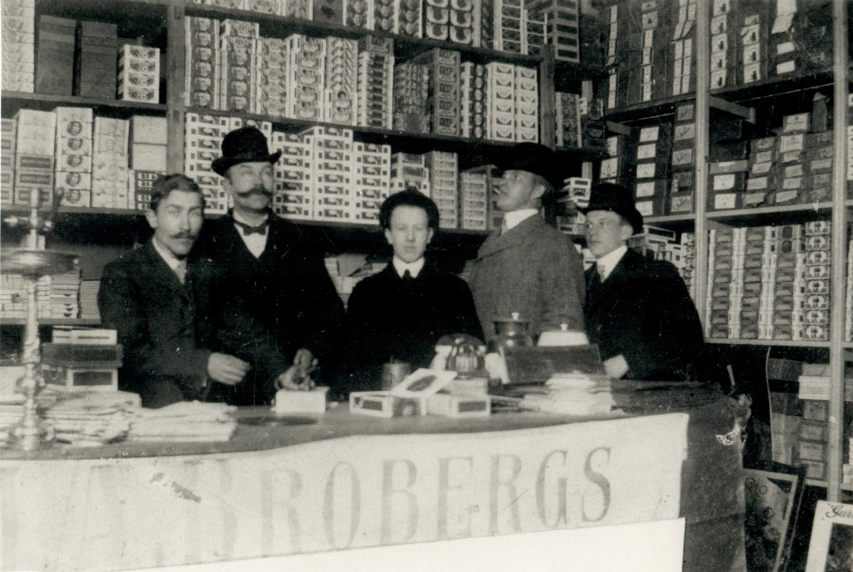 Fem män bakom disken i en tobakshandel, tidigt 1900-tal.