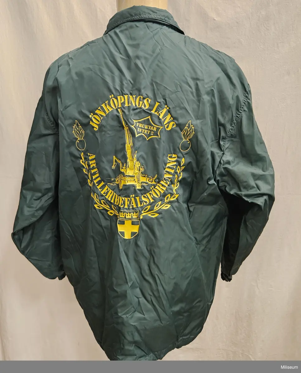 Vindtygsjacka med text "Jönköpings Läns Artilleribefälsförening" tryckt på ryggen. Storlek M.