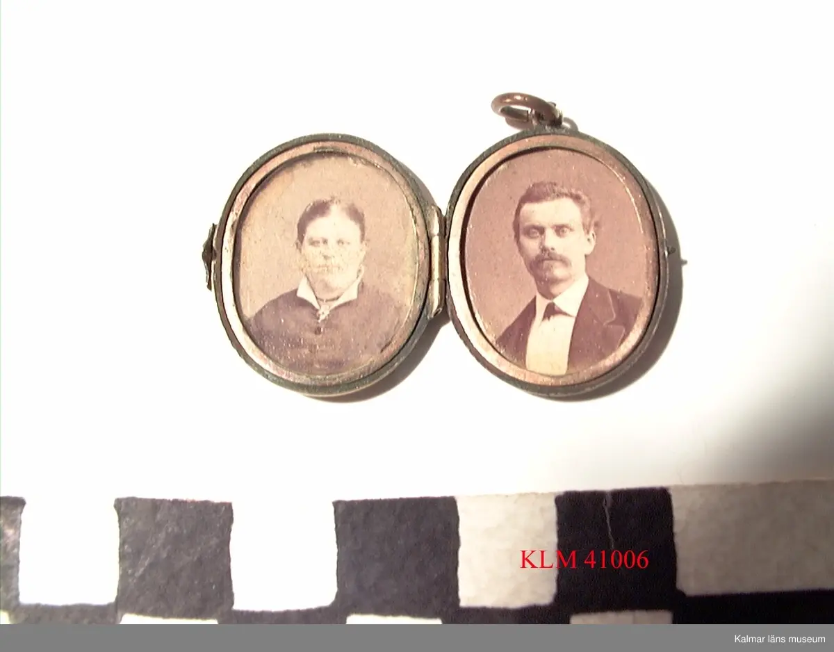 KLM 41006 Medaljong, metall. Utsidan med graverad dekor, bl a en brevduva. Inuti fotografier av Stina Wimmerströms farföräldrar, Carolina och Carl Wimmerström.