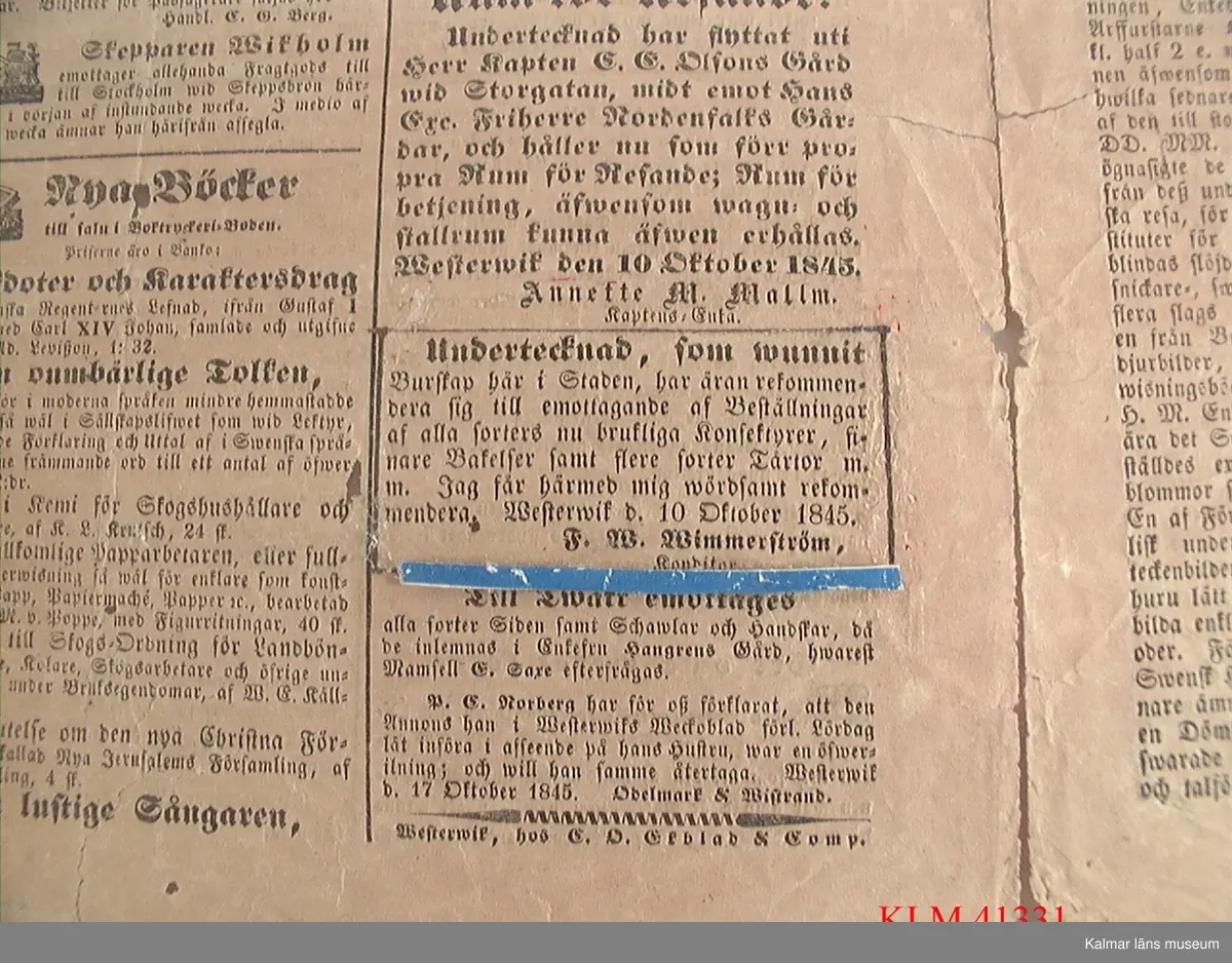 KLM 41331 Tidning, papper. Fyrsidigt tryck utvikt och inramat bakom glas i brun träram. Westerwiks Weckoblad från lördagen den 18 oktober 1845. På sista sidan är en annons markerad där konditor F.W. Wimmerström erbjuder sina tjänster. Fredrik Wilhelm Wimmerström var Stina Wimmerströms farfarsfar.