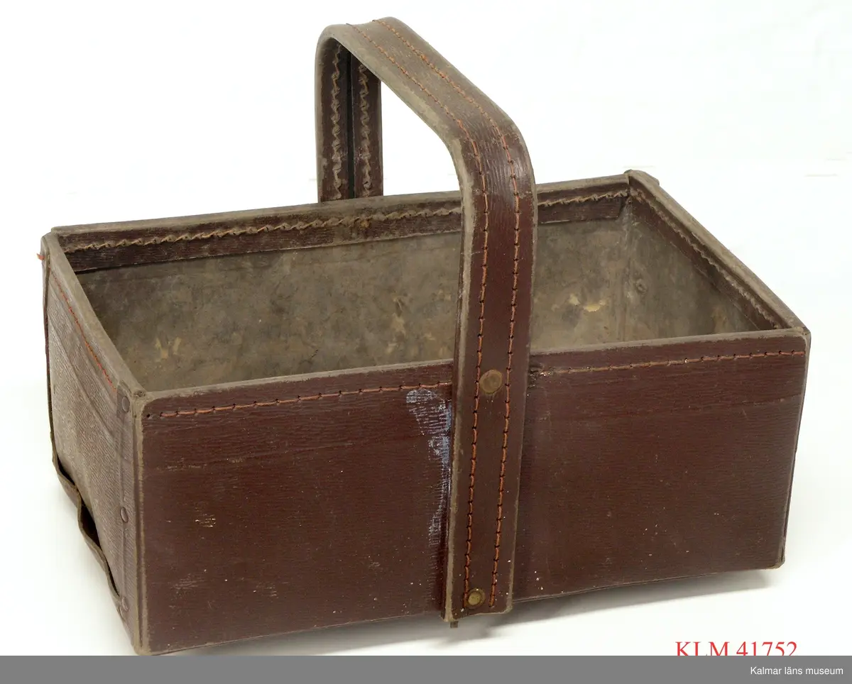 KLM 41752 Korg, papp. Rektangulär korg med tvärställd grepe, vikt av brun papp och nitad.