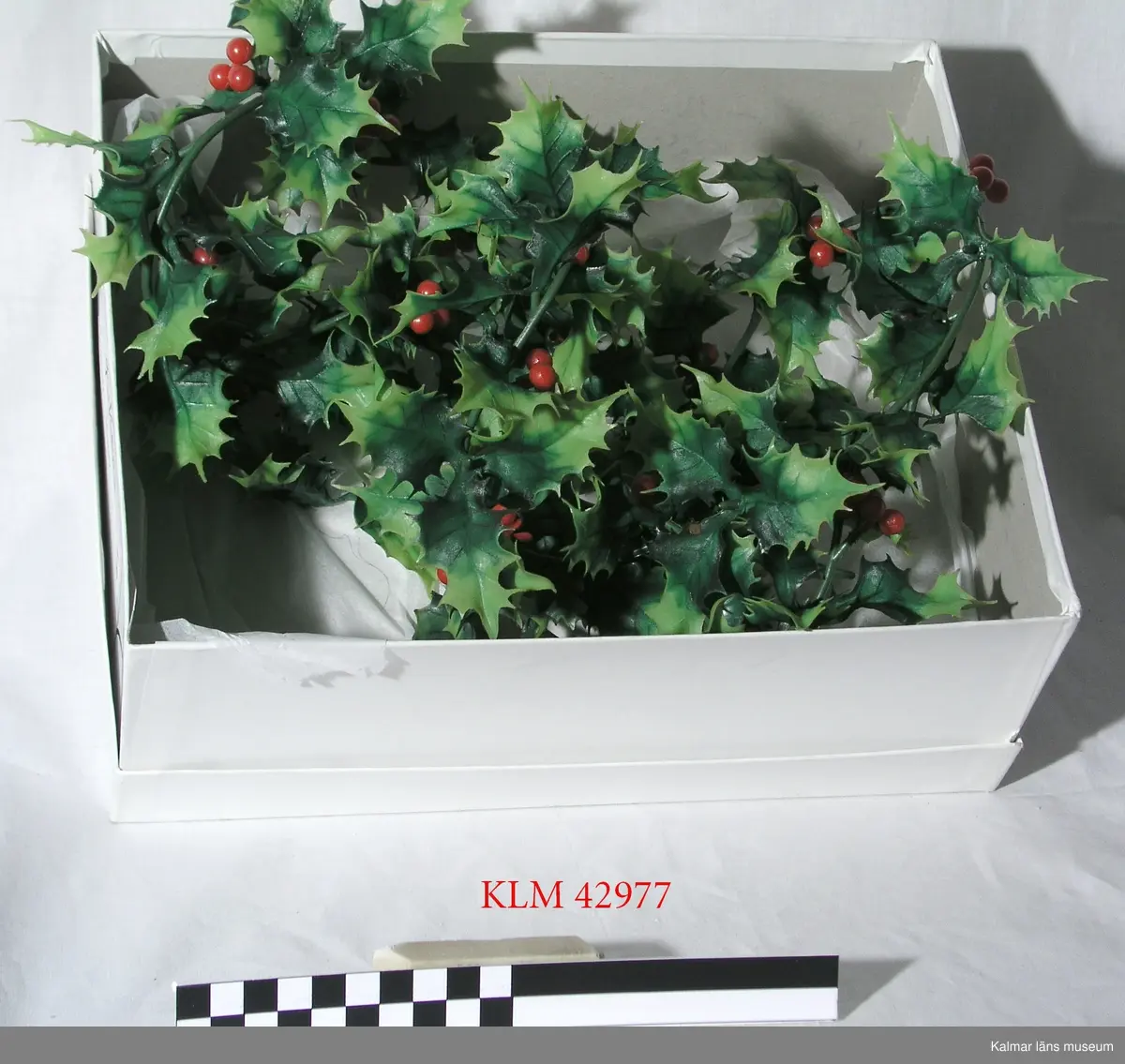 KLM 42977 Julprydnad, plast. Girlang av grön plastlina med påfästa gröna blad och röda bär som imiterar järnek.