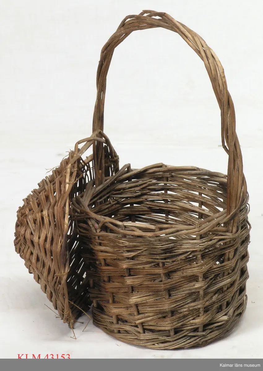 KLM 43153 Korg, trä. Liten rund korg, spiralflätad av vidjor. Med hög grepe och toppigt lock fäst vid grepen.