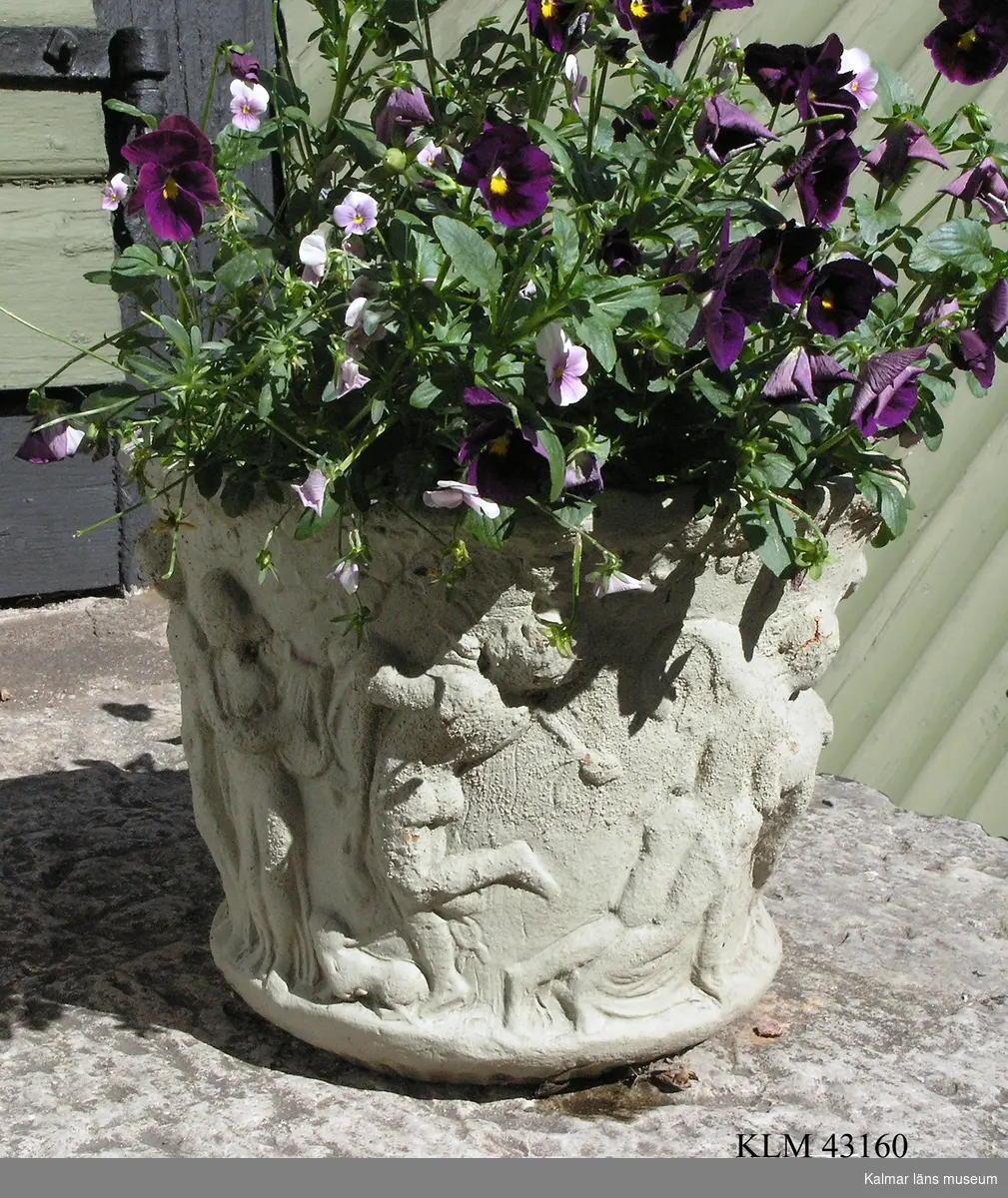 KLM 43160 Trädgårdsurna, keramik. Rund, svagt vidgande uppåt, med motiv från antiken: man som spelar panflöjt samt danserskor m.m.