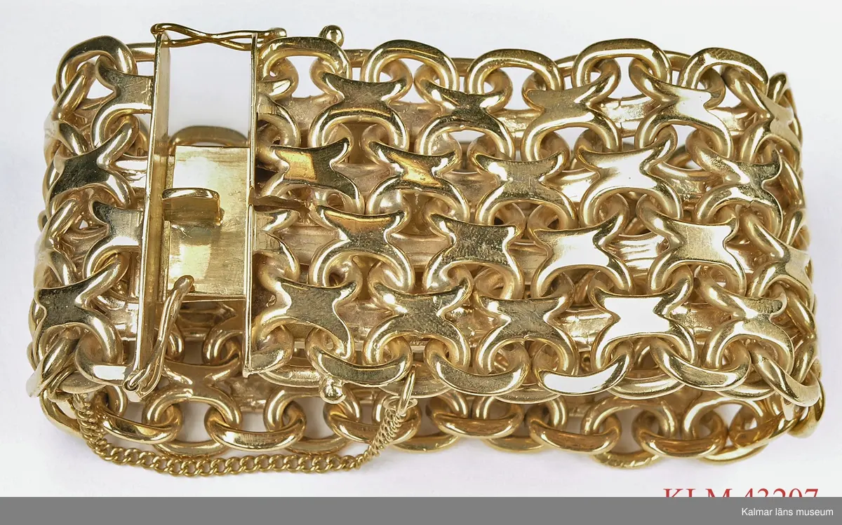 KLM 43207 Armband, guld. Bred krysslänk, kraftigt lås med säkerhetskedja. Stämplar: otydlig tillverkarstämpel, stadsstämpel, "18K", "I9" = 1959 samt tre kronor.