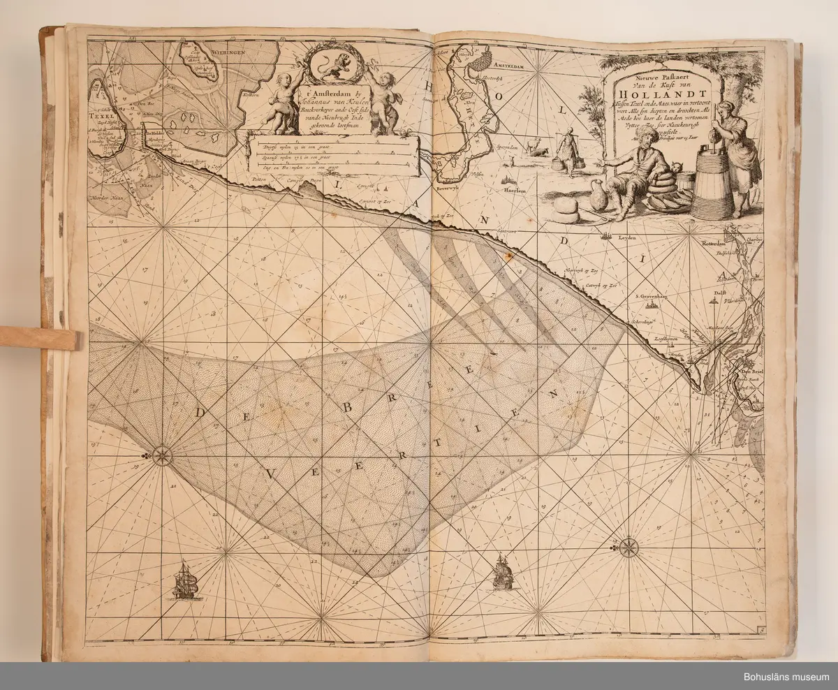 Holländskt sjökort i två sammanbundna delar, tryckta 1697 i Amsterdam.
Brunt skinnband av pergament i relativt gott skick med upphöjda bind. Text på nederlänska  i frakturstil med rikt illustrerade kartblad, ofta utvikbara. Restaurerad hos papperskonservator. 

Handanteckningar på pärmsidans insida:  
William Andrew Macfie 
Anfasteröd.
Till museum 14/9 64

Tryckt text på titelbladet första delen: 
De nieuwe groote lichtende zee-fackel, ´t derde deel. Verthoonende de kulten van Granada, Catalonien, Provence, Italien, Dalmatien, Grieken, Thracien, Anatolien, Syrien, Egypten, en de geheele noordkust van Barbaryen, met alle haer onderbehoorende en ... leggende eylanden. Als mede de beschrijvingh van alle havenen, bayen, reeden, drooghten, diepten, streckingen en opdoeningen van landen. Op de ware pools hoogte geleyd. Uyt ondervindinge van veel ervarene stuurlieden, lootsen en liefhebbers der zeevaert, vergadert door Claas Jansz. Vooght ... – 

T´Amsteldam, gedruckt by Joannes van Keulen, boeck-en zee-kaert-verkoper, aen de Nieuw-brugh, in de gekroonde lootsman, 1697, 1697 - 4], 29 s., s. 26, s. 31-92, s. 1-22, s. 1-20, [80] pl.-bl : kartor

Tryckt på titelbladet andra delen:
De nieuwe groote lichtende zee-fakkel, ´t tweede deel. Verthoonende de zee-kusten van het zyderste gedeelte van de Noord-zee, ´t Canaal, ´t westersche gedeelte van Engeland en Schotland, Yrland, Vrankrijk, Spanjen, Marocco, Gualata, Genehoa en Gambia, met de onder-vehoorige eylanden,mitsgaders ve vlaamsche, canarische en soute Eylanden. Als mede de ... van alle havenen, bayen, reeden, droogten, diepten, streckingen en opdoeningen van landen, op de ware pools hoogte geleyd, uptonderbindinge van veele ervarene stuurlieden, lootsen en lief-hebbers der zee-vaart. Zijnde van alle ... door Claes Jansz. Vooght ... - T´Amsterdam, gedrukt by Joannes van Keulen, boek zee-kaart-verkooper, en graadboogmaker aan de oost-zyde van de Nieuw-brug, in de gekroonde lootsman, 169.., 169n - 4], 4 s., s. 7-34, s. 53, s. 36, s. 35, s. 38, s. 35, s. 40-85, s. 68, s. 87-91, s. 29, s. 93-97, [87] pl.-bl : kartor