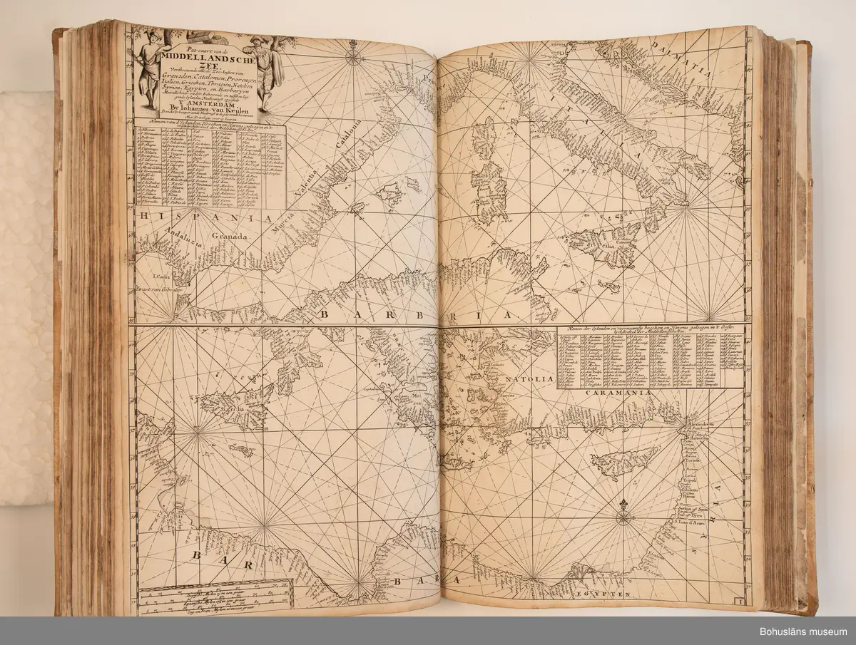 Holländskt sjökort i två sammanbundna delar, tryckta 1697 i Amsterdam.
Brunt skinnband av pergament i relativt gott skick med upphöjda bind. Text på nederlänska  i frakturstil med rikt illustrerade kartblad, ofta utvikbara. Restaurerad hos papperskonservator. 

Handanteckningar på pärmsidans insida:  
William Andrew Macfie 
Anfasteröd.
Till museum 14/9 64

Tryckt text på titelbladet första delen: 
De nieuwe groote lichtende zee-fackel, ´t derde deel. Verthoonende de kulten van Granada, Catalonien, Provence, Italien, Dalmatien, Grieken, Thracien, Anatolien, Syrien, Egypten, en de geheele noordkust van Barbaryen, met alle haer onderbehoorende en ... leggende eylanden. Als mede de beschrijvingh van alle havenen, bayen, reeden, drooghten, diepten, streckingen en opdoeningen van landen. Op de ware pools hoogte geleyd. Uyt ondervindinge van veel ervarene stuurlieden, lootsen en liefhebbers der zeevaert, vergadert door Claas Jansz. Vooght ... – 

T´Amsteldam, gedruckt by Joannes van Keulen, boeck-en zee-kaert-verkoper, aen de Nieuw-brugh, in de gekroonde lootsman, 1697, 1697 - 4], 29 s., s. 26, s. 31-92, s. 1-22, s. 1-20, [80] pl.-bl : kartor

Tryckt på titelbladet andra delen:
De nieuwe groote lichtende zee-fakkel, ´t tweede deel. Verthoonende de zee-kusten van het zyderste gedeelte van de Noord-zee, ´t Canaal, ´t westersche gedeelte van Engeland en Schotland, Yrland, Vrankrijk, Spanjen, Marocco, Gualata, Genehoa en Gambia, met de onder-vehoorige eylanden,mitsgaders ve vlaamsche, canarische en soute Eylanden. Als mede de ... van alle havenen, bayen, reeden, droogten, diepten, streckingen en opdoeningen van landen, op de ware pools hoogte geleyd, uptonderbindinge van veele ervarene stuurlieden, lootsen en lief-hebbers der zee-vaart. Zijnde van alle ... door Claes Jansz. Vooght ... - T´Amsterdam, gedrukt by Joannes van Keulen, boek zee-kaart-verkooper, en graadboogmaker aan de oost-zyde van de Nieuw-brug, in de gekroonde lootsman, 169.., 169n - 4], 4 s., s. 7-34, s. 53, s. 36, s. 35, s. 38, s. 35, s. 40-85, s. 68, s. 87-91, s. 29, s. 93-97, [87] pl.-bl : kartor