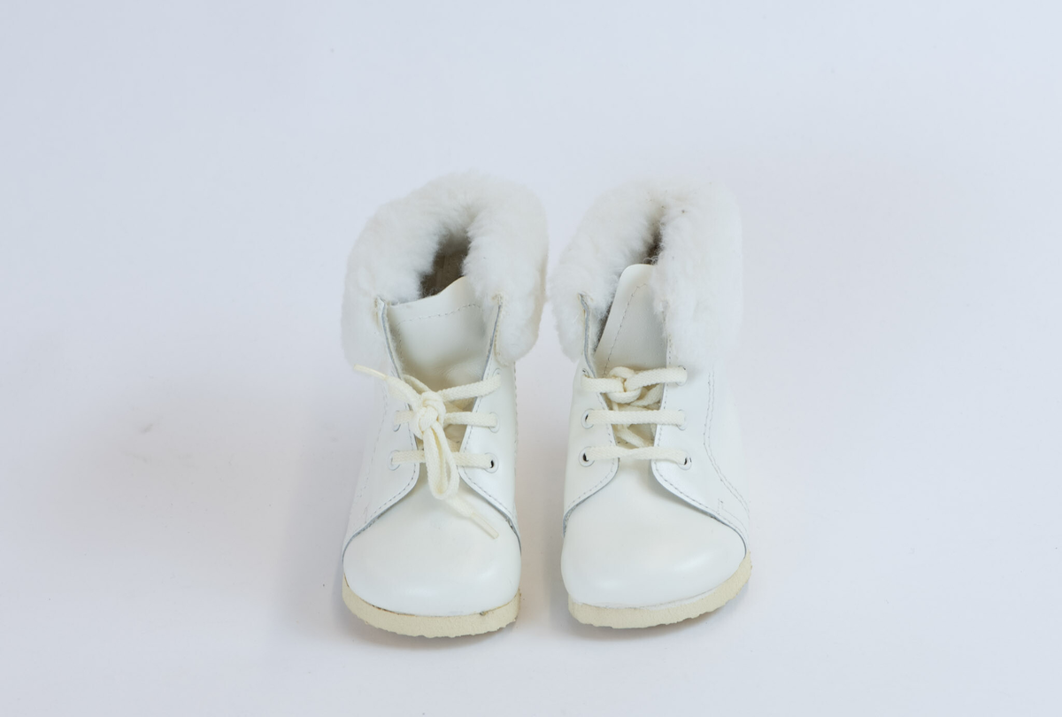 Babystøvletter i originaleske, str. 22. Snørt gjennom 4 par metallmaljer. På hver side to dekorsømmer fra øvrekant til såle. Skoen sydd av fire deler, to sidestykker, tåstykke, som er påsydd pløse. Innvendig foret med loddent syntetisk stoff, langs øvrekant en bred remse syntetisk pels. Ruglete såle.
