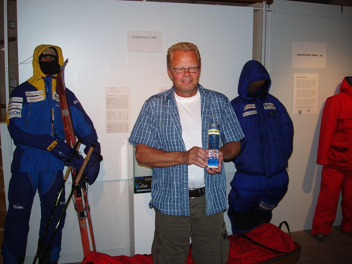 En man med glasögon, i rutig kortärmad skjorta utanpå en vit t-shirt, håller en plastflaska med vatten märkt "Absolut Nordpolen 8 april 2008 kl 17.00", som han skänker till Grenna Museum.