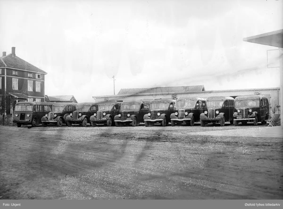 Busser oppstilt foran bussgarasje, antakelig Ørje, Marker 1938-39. 
Bussene gikk i ruter mellom disse stedene Mysen - Ørje - Töcksfors -Oslo.
Fra venstre: 
B-14294 Reo 1938 Mysen - Ørje - Töcksfors
B-15111 Reo 1936 Töcksfors - Ørje - Mysen
B-15232 Reo 1936 Töcksfors - Ørje - Oslo
A-6851 Reo 1936 Turbil
A-6839 Reo 1938 Kringsjå reisebyrå
Uregistrert Reo 1938  skilt Töcksfors - Ørje - Oslo
Uregistrert Reo 1938
B-15257 Reo 1936
B-14569 Oldsmobile 1938 

Reklameskilt for Castrol.