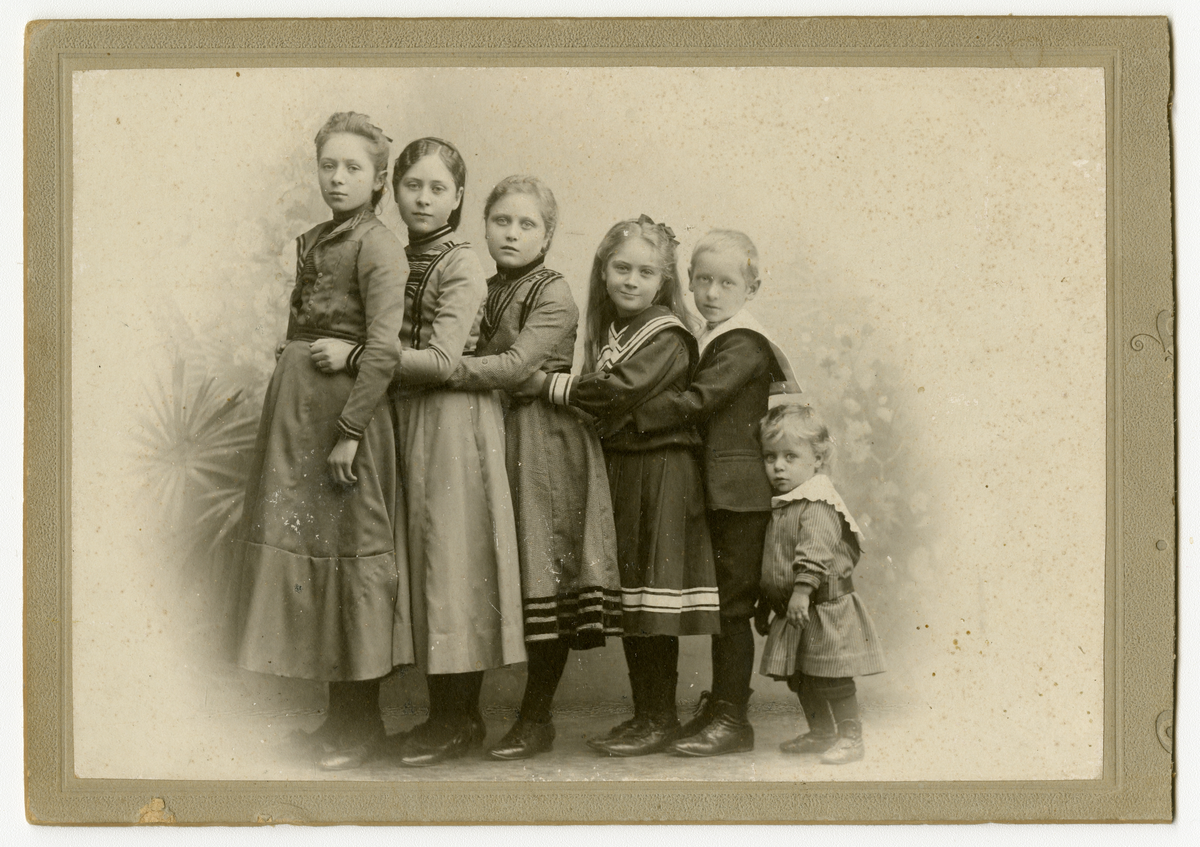 Kabinetkortfoto av ukjent søskengruppe. Barna står i rekke fra eldst til yngst