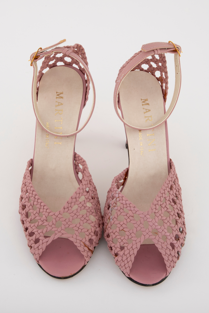 Rottingflettet selskapssandeler med ankelstropp, åpen tå og stiletthæl. Både hælkappe og forblad er utført i kurvfletting, mens hæl og ankelstropp er i glatt skinn. Ankelstroppen reguleres med på yttersiden med spenne av gullfarget metall. Innvendig fôret med blek syrinfarget, imitert skinn, før påføring av et ytre lag med kremfarget, imitert skinn. Kun den åpne tåen er fortsatt syrinfarget. Både overside og såle er av syntetmaterilale. Str. 37. Sålen er av naturfarget, glatt lærimitasjon, med svartmalt ytterkant.

Originaleske følger med, se NK2002-206-002