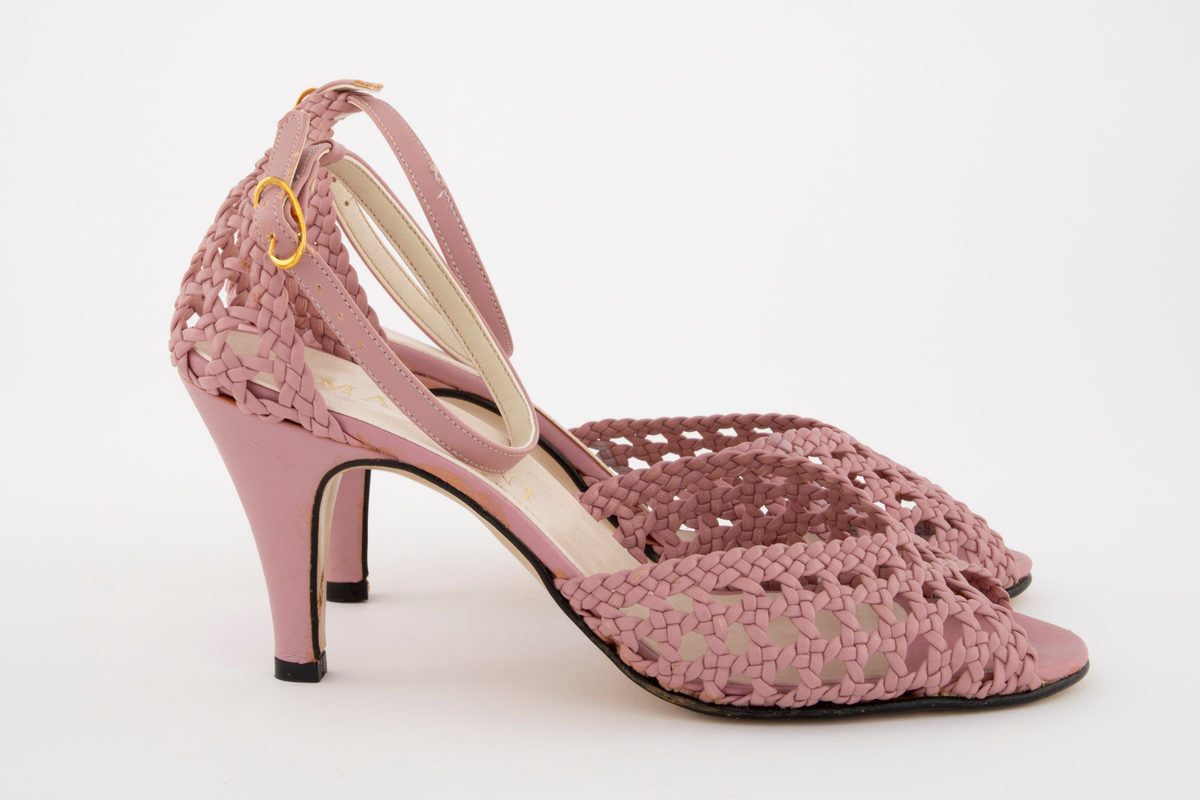 Rottingflettet selskapssandeler med ankelstropp, åpen tå og stiletthæl. Både hælkappe og forblad er utført i kurvfletting, mens hæl og ankelstropp er i glatt skinn. Ankelstroppen reguleres med på yttersiden med spenne av gullfarget metall. Innvendig fôret med blek syrinfarget, imitert skinn, før påføring av et ytre lag med kremfarget, imitert skinn. Kun den åpne tåen er fortsatt syrinfarget. Både overside og såle er av syntetmaterilale. Str. 37. Sålen er av naturfarget, glatt lærimitasjon, med svartmalt ytterkant.

Originaleske følger med, se NK2002-206-002