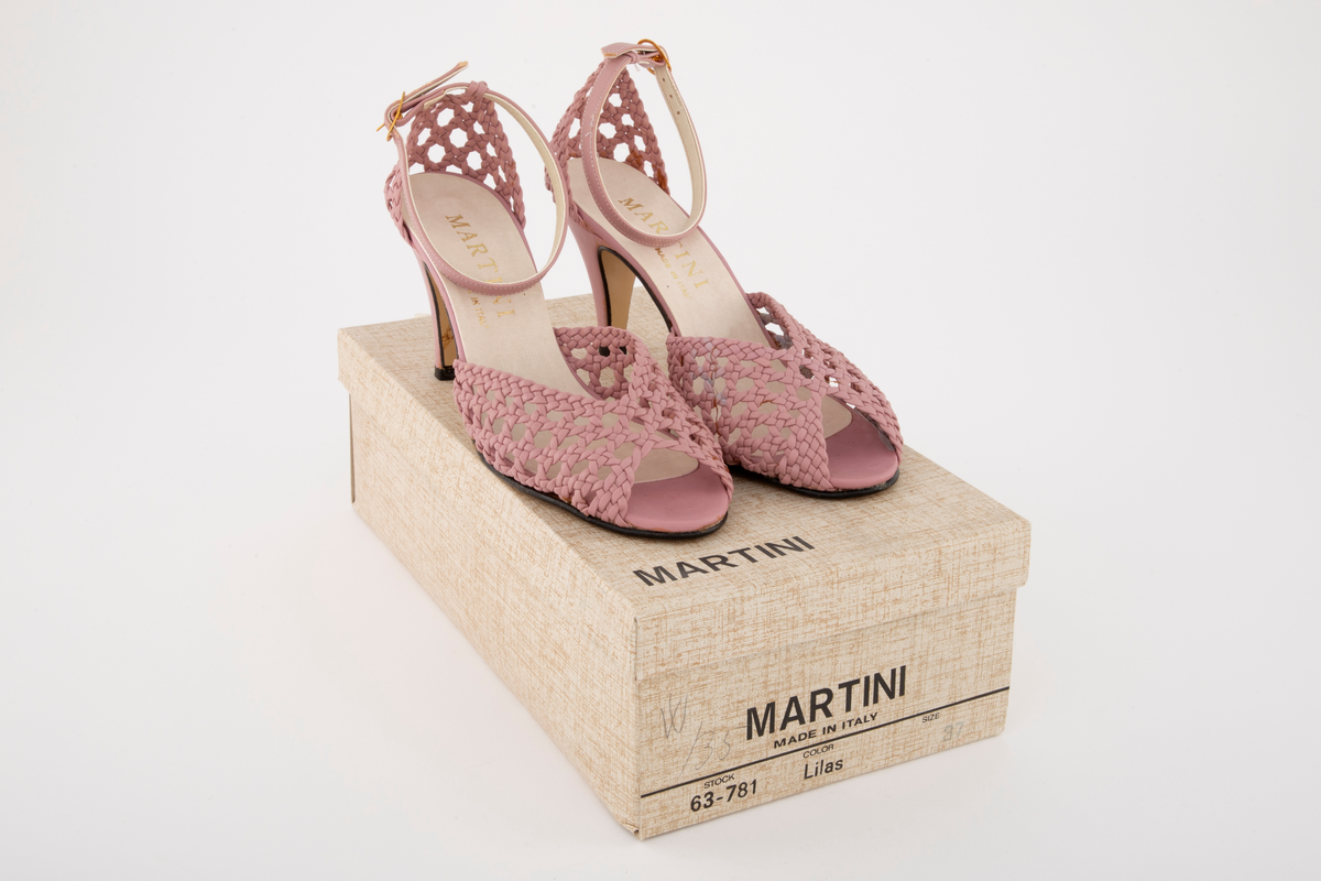 Rottingflettet selskapssandeler med ankelstropp, åpen tå og stiletthæl. Både hælkappe og forblad er utført i kurvfletting, mens hæl og ankelstropp er i glatt skinn. Ankelstroppen reguleres med på yttersiden med spenne av gullfarget metall. Innvendig fôret med blek syrinfarget, imitert skinn, før påføring av et ytre lag med kremfarget, imitert skinn. Kun den åpne tåen er fortsatt syrinfarget. Både overside og såle er av syntetmaterilale. Str. 37. Sålen er av naturfarget, glatt lærimitasjon, med svartmalt ytterkant.

Originaleske følger med, se NK2002-206-002