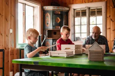 Barn bygger med laftestasjonen i Berganstua sammen med besteforeldre