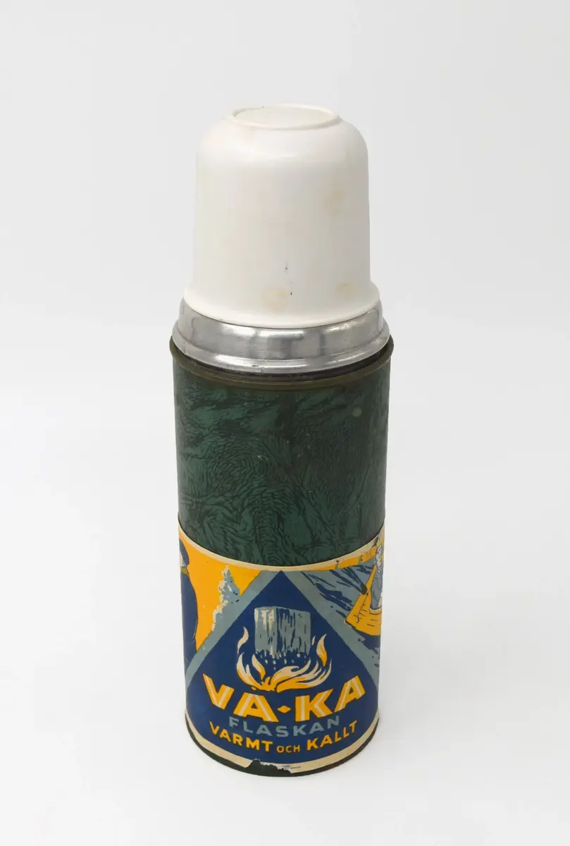 Termos inklädd i grönt marmorerat papper och vitt plastlock. Nedre delen illustrativ bred border som löper längs flaskans omkrets i färgerna gult, blått (ljus och mörk) samt vitt. 

Mitten visar ett isblock med en eld under och texten: "VA-KA FLASKAN VARMT och KALLT". 
Till vänster om denna illustration, en man och kvinna i vinterkläder med vinterlandskap bakom. Kvinnan häller över dryck från en termos till mannens dryckeskärl. Tillhörande text: " FÖR VARMA DRYCKER".
På andra sidan, en man i byxor och tröja samt en kvinna med klänning på en båt. Kvinnan häller över dryck från en termos till mannens dryckeskärl. Tillhörande text: " FÖR KALLA DRYCKER".

Öppningen av termosen stängs med en kord och därefter det vita plastlocket. 

