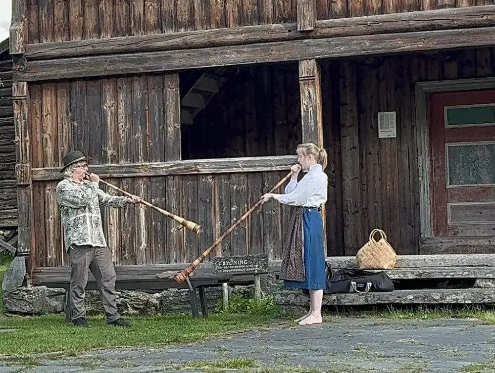 En mann og en kvinne foran et gammelt hus som spiller på lur