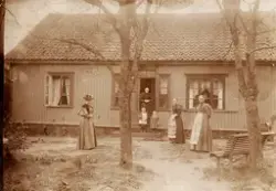 St. Marie gate (fra 1910 nr. 71), havesiden
I døråpningen: Anne Marie Andresen, født Klausen 1819. Hun var gift med huseier og kirkesanger Karsten Andresen. Til venstre: hennes svigerdatter, Fanny Andresen, født 1870 (gift med Christian Andresen). På trappa hennes to barn, Thorleif (f. 1892) og Ingrid (født 1894). Til høyre: Anne Maries døtre, Julie Marie (født 1849) og Augusta Karine Andresen (født 1851)