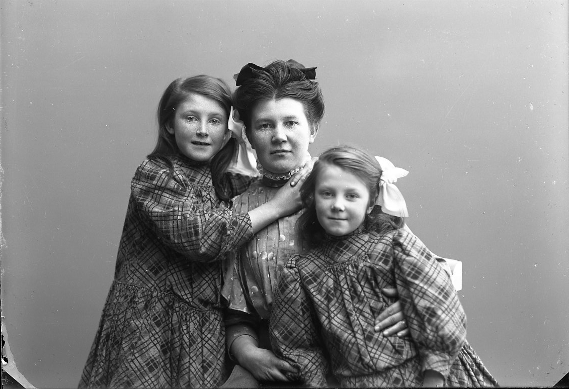 En kvinna med hennes två små döttrar intill sig.