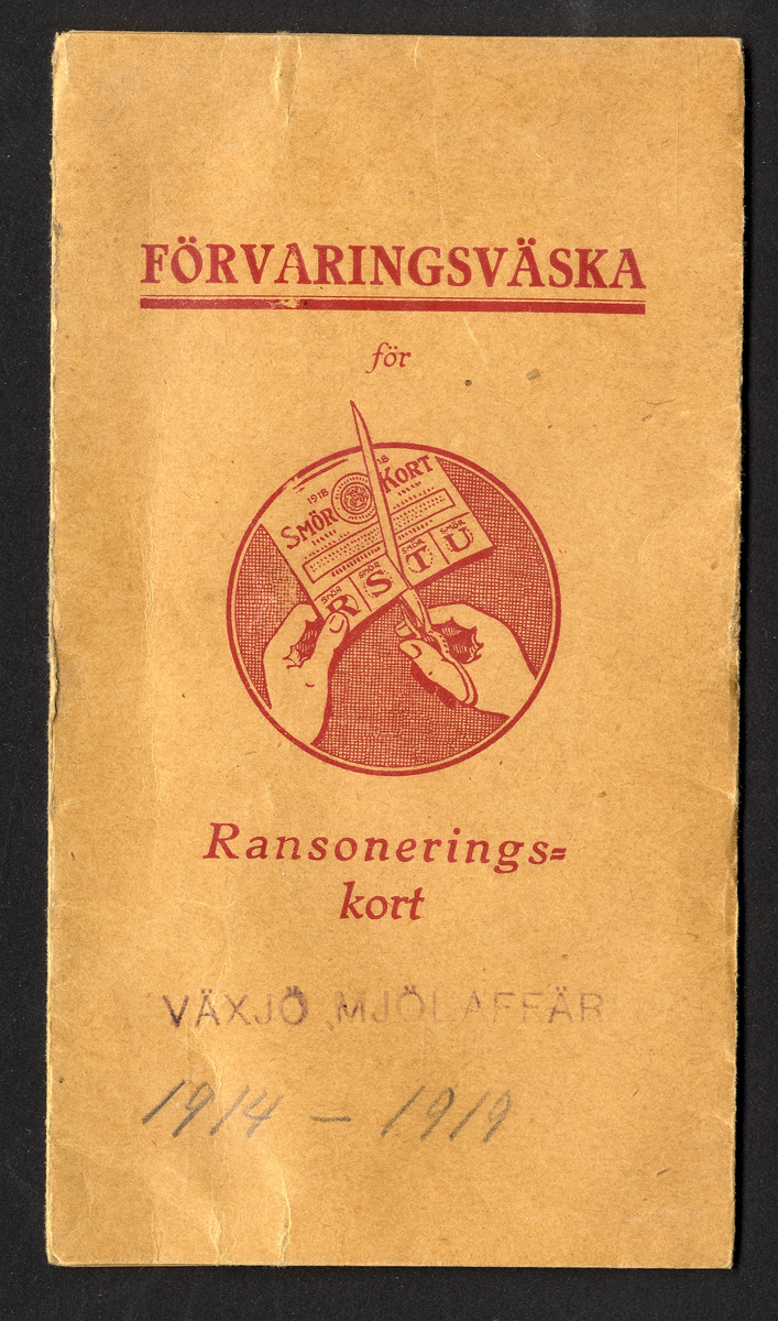 Förvaringsväska i papper för ransoneringskort (märkt "Växjö Mjölaffär 1914-1919" i blyerts).
Innehåller: 
Sockerkort (6 st. gröna, 10 st. svarta), sockerkort (syltsocker) 3 st., sockerkort (avlånga) 2 st..
Brödkort 5 st., Påbrödskort 5 st.. Kaffekort 2 + 3 st. Sirapskort 1.