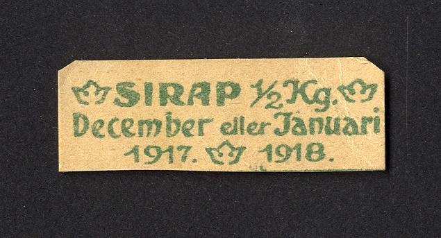 Förvaringsväska i papper för ransoneringskort (märkt "Växjö Mjölaffär 1914-1919" i blyerts).
Innehåller: 
Sockerkort (6 st. gröna, 10 st. svarta), sockerkort (syltsocker) 3 st., sockerkort (avlånga) 2 st..
Brödkort 5 st., Påbrödskort 5 st.. Kaffekort 2 + 3 st. Sirapskort 1.