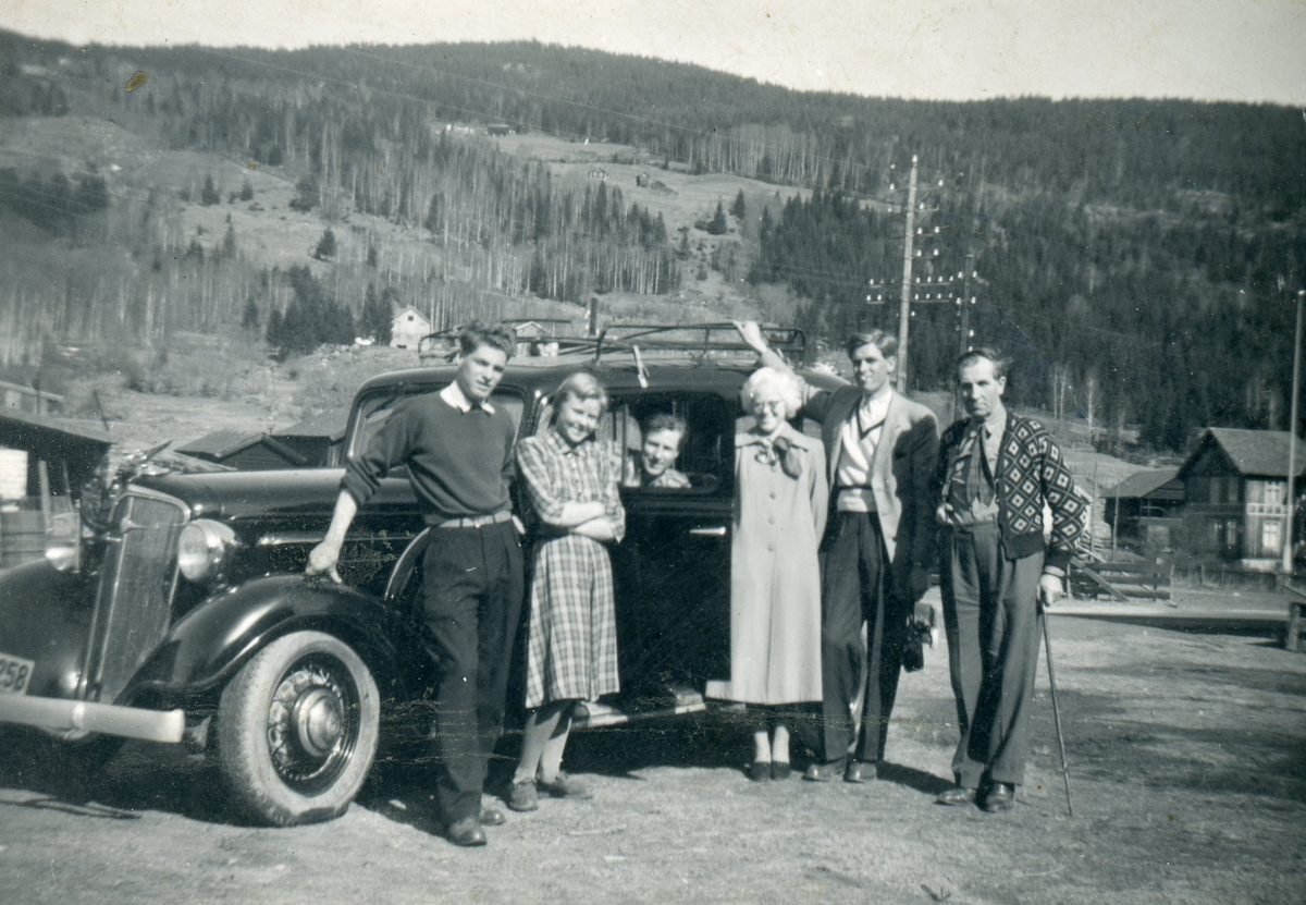 Frå h. Nils O. Hoftun, Ola N. Hoftun, Kristi Frøysok Hoftun, Embrik N. Hoftun, Sigrid Hoftun Johnsen, Harald N. Hoftun. Dei står framfor en Chevrolet 1934-modell.