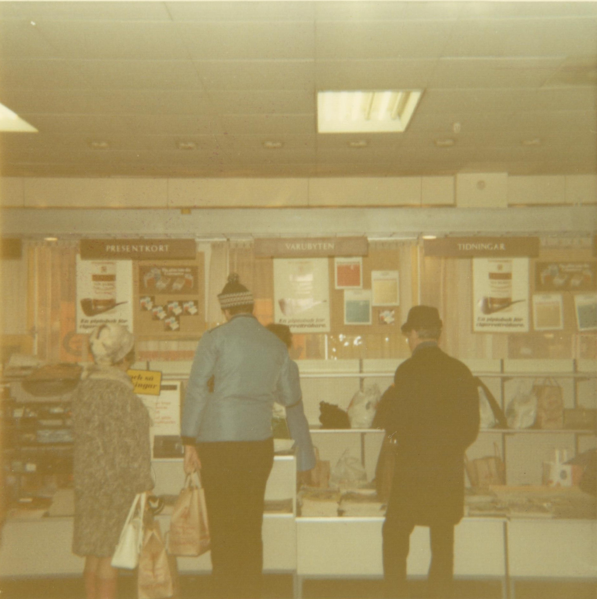 Kunder betjänas i Tempo-butiken i Umeå, november 1970. Bakom kassan hänger tobaksreklam.