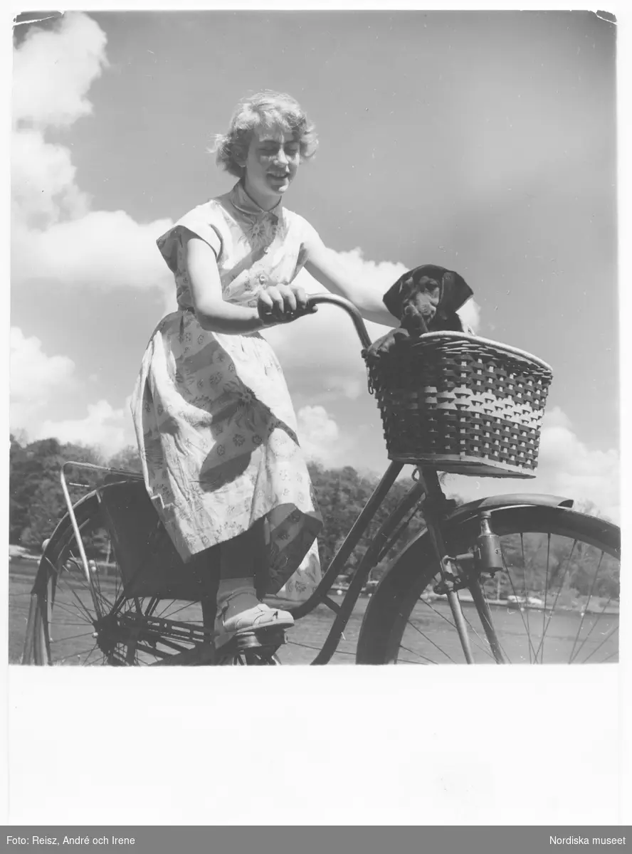 Kvinna på cykelutflykt med en hund i cykelkorgen.