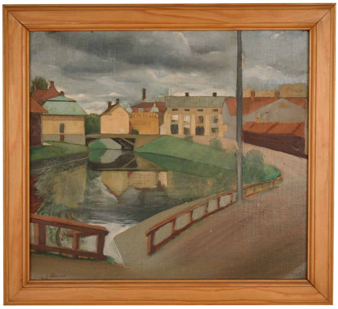 Bebyggelse längs ån som rinner genom Falun, Faluån, under grå regnmoln.