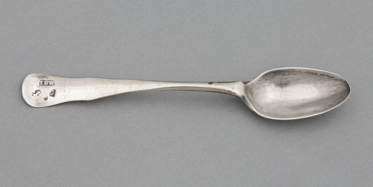 Tesked i silver.
Slät modell, utan markerad ås på framsidan. Stämplar på skaftets översida.

Inskrivet i huvudbok 1876