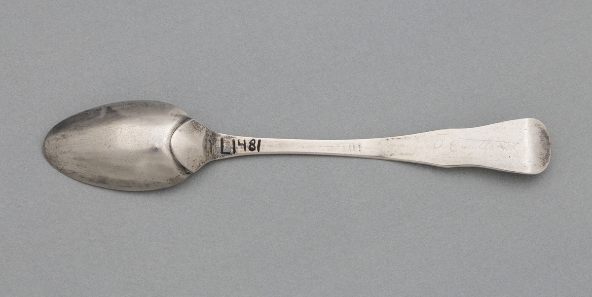 Tesked i silver.
Slät modell, utan markerad ås på framsidan. Stämplar på skaftets översida.

Inskrivet i huvudbok 1876