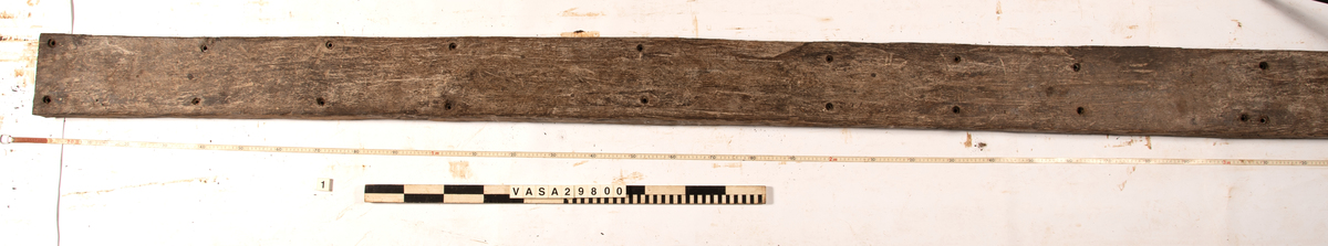 Däcksplanka.
27 genomgående spikhål. Spikhålen är original från när skeppet byggdes. Originalspikarna är bortrostade. Efter bärgningen monterades däcksplankan med rostfri fransk träskruv samt bricka. Vid demonteringen 2023 lossades alla skruvar. De brickor som gick att ta bort togs bort. En del satt så djupt i träet att det inte gick att demontera dem utan att skada plankan. Dessa brickor fick därför sitta kvar. 
Tydliga avtryck från balkar och ribbor på undersidan som även är täckt av ytliga sprickor och har rostfläckar.
