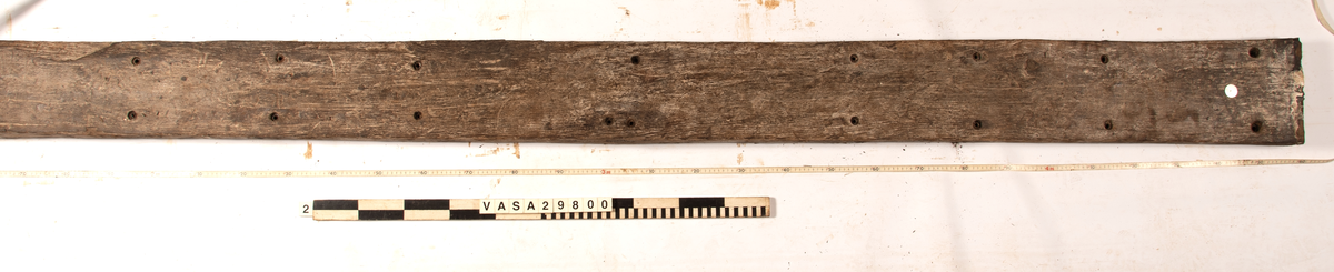 Däcksplanka.
27 genomgående spikhål. Spikhålen är original från när skeppet byggdes. Originalspikarna är bortrostade. Efter bärgningen monterades däcksplankan med rostfri fransk träskruv samt bricka. Vid demonteringen 2023 lossades alla skruvar. De brickor som gick att ta bort togs bort. En del satt så djupt i träet att det inte gick att demontera dem utan att skada plankan. Dessa brickor fick därför sitta kvar. 
Tydliga avtryck från balkar och ribbor på undersidan som även är täckt av ytliga sprickor och har rostfläckar.