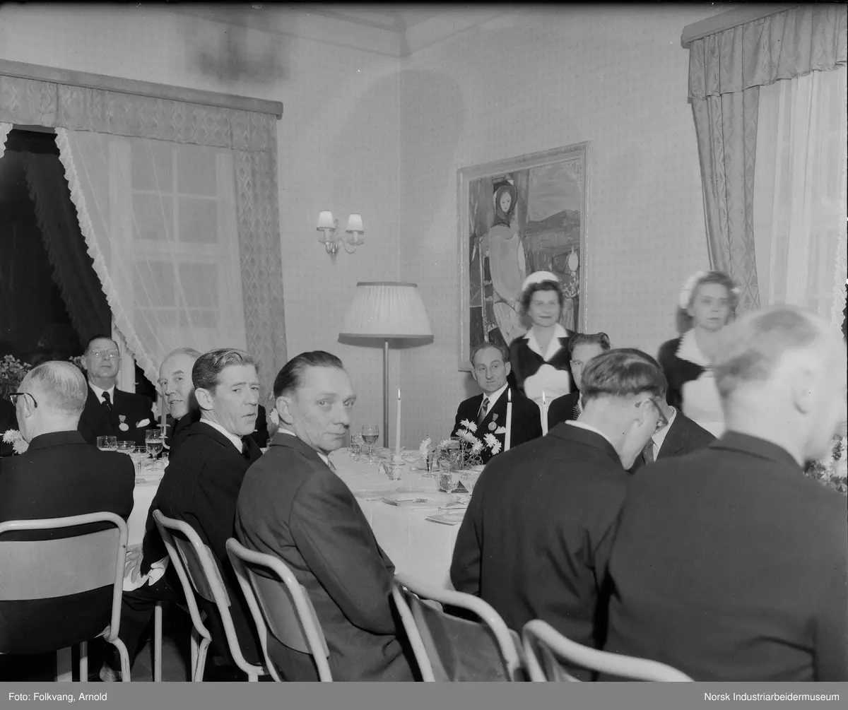 Jubilantfest 1957, herrer. Menn sittende til bords på Rjukan Admini. Bordet er dekket til fest. Kvinnelig serveringspersonale gående ved bordet.