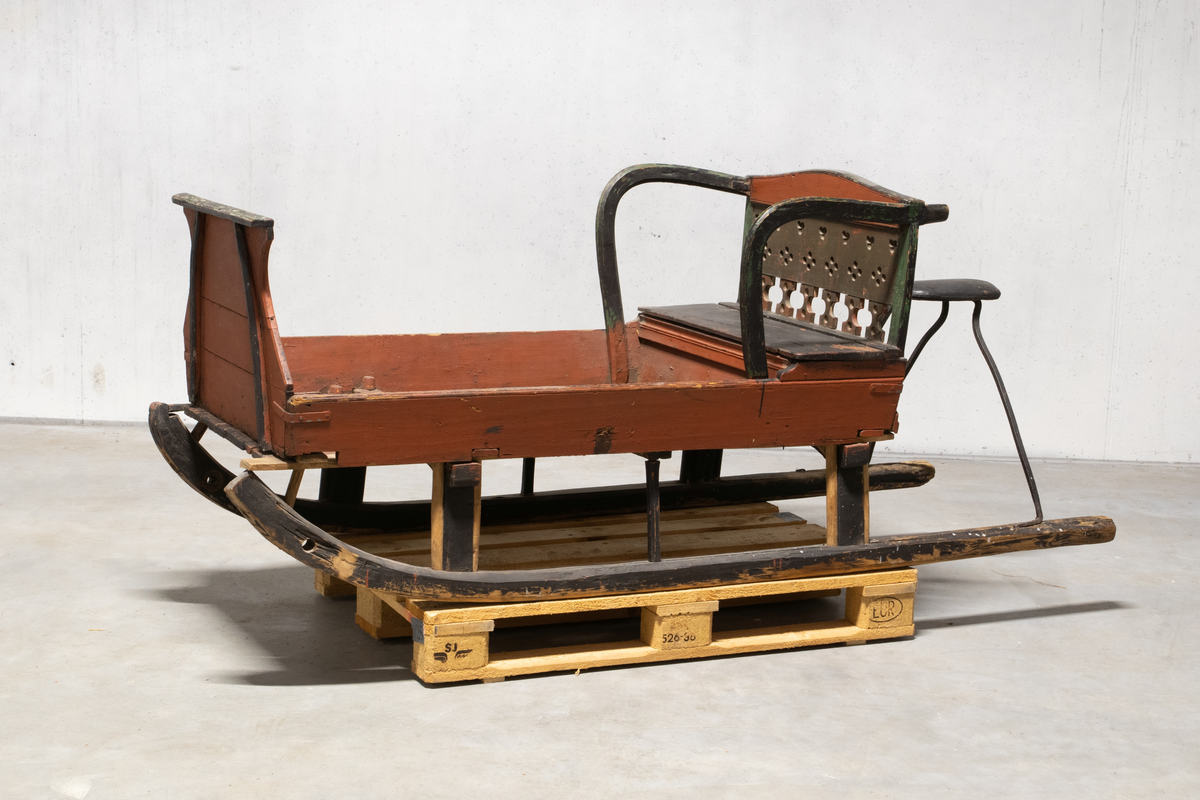 Kjelke med plan toppflate som har lave karmer på langsidene, høyt frontorett med rett topp og sveifede sidekanter. Bakerst på sluffeplanet kasseformet sete med hengslet lokk. Setet har gjennombrutt rygg og bøyleformede sidevanger. Bak på meiene skinnbetrukket kuskesete som hviler på tre bøyde jernstenger.