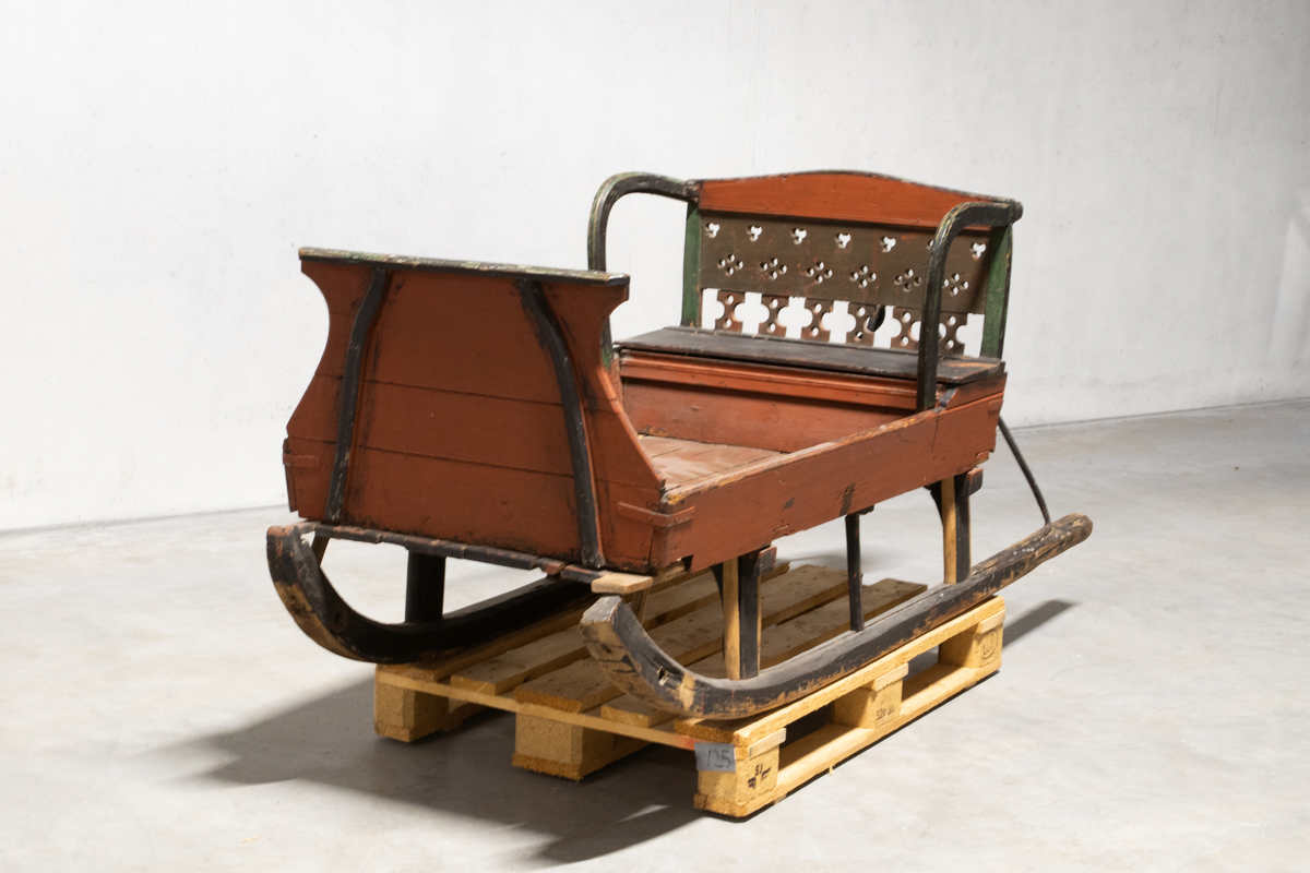 Kjelke med plan toppflate som har lave karmer på langsidene, høyt frontorett med rett topp og sveifede sidekanter. Bakerst på sluffeplanet kasseformet sete med hengslet lokk. Setet har gjennombrutt rygg og bøyleformede sidevanger. Bak på meiene skinnbetrukket kuskesete som hviler på tre bøyde jernstenger.