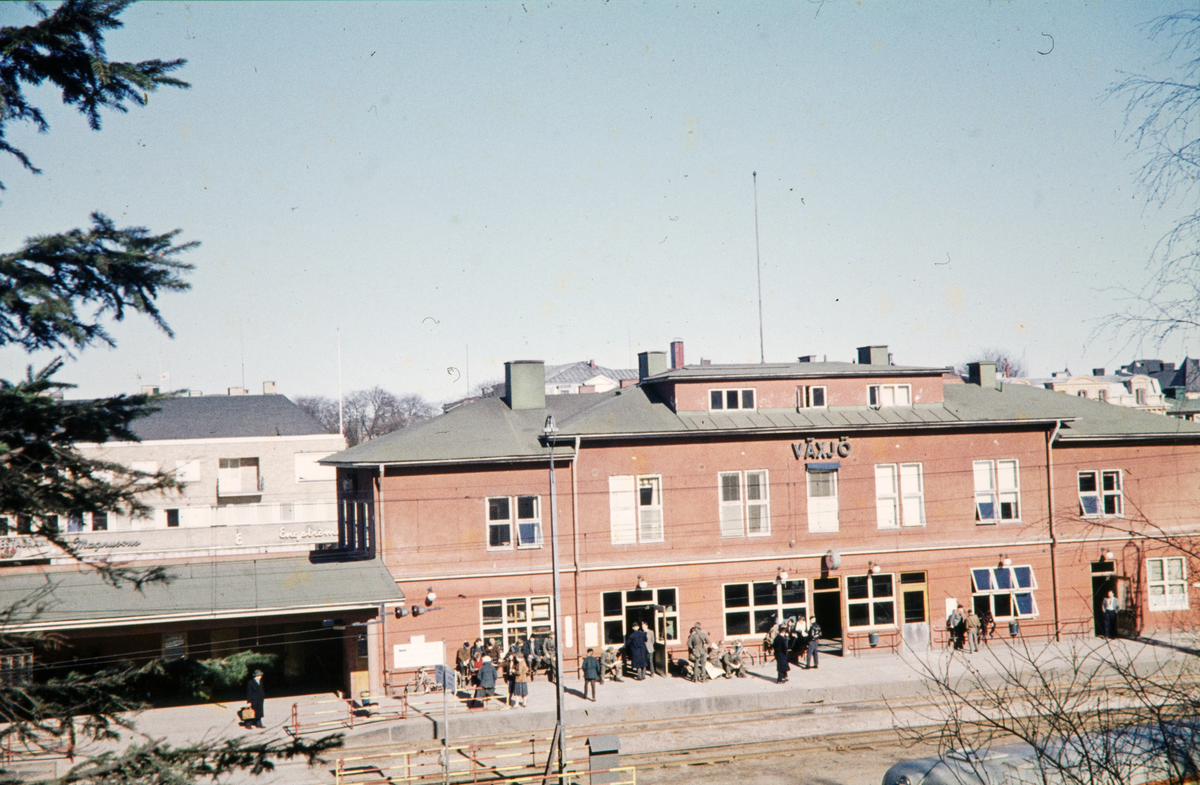 Järnvägsstationen, Växjö, från Museiparken. I bakgrunden skymtar man bl a den nya fastigheten i hörnet Norra Järnvägsgatan/Kungsgatan.
Färgfoto ca 1960.