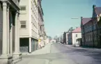 Kungsgatan, Växjö, i korsningen Kungsgatan/Norrgatan. Till vänster skymtar Frimurarhuset och till höger syns den s.k. Sjögrenska skolan m.m.
Färgfoto ca 1965.