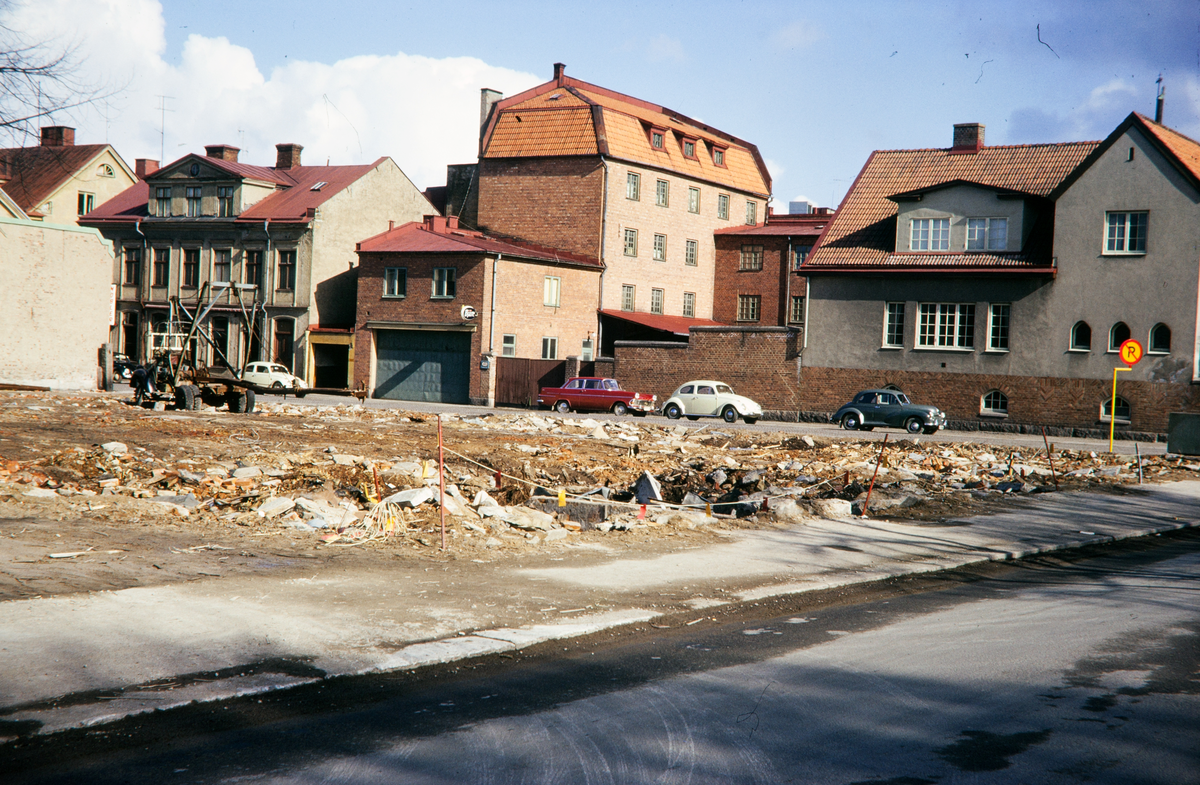 Rivningsverksamhet i kvarteret Fries vid Sandgärdsgatan. korsningen mot Västergatan. I bakgrunden syns några husen i kvarteret Stormen. 
Färgfoto ca 1965.