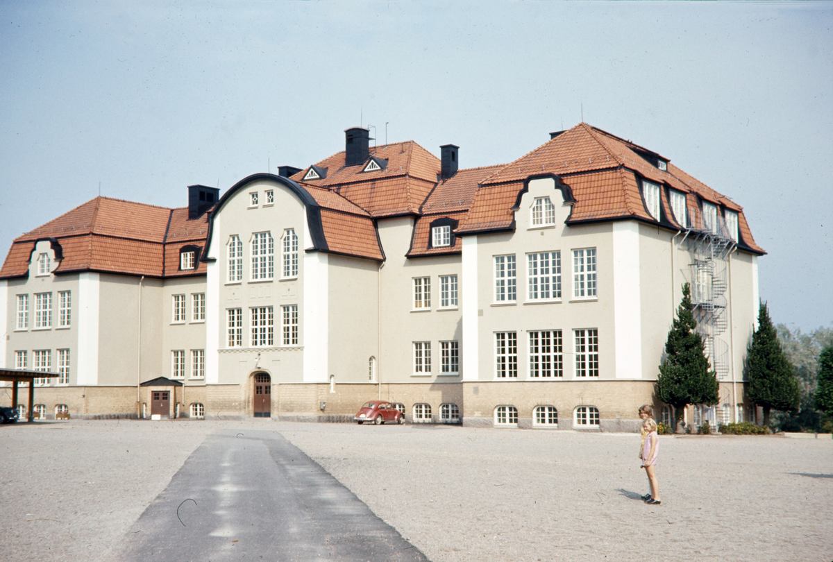 Bäckaslövskolan, Växjö. Skolan byggdes under 1:a världskriget och inrymde Kronobergs regemente tills de nya kasernerna för regementet var färdigställda 1920-21. 
Färgfoto ca 1958.