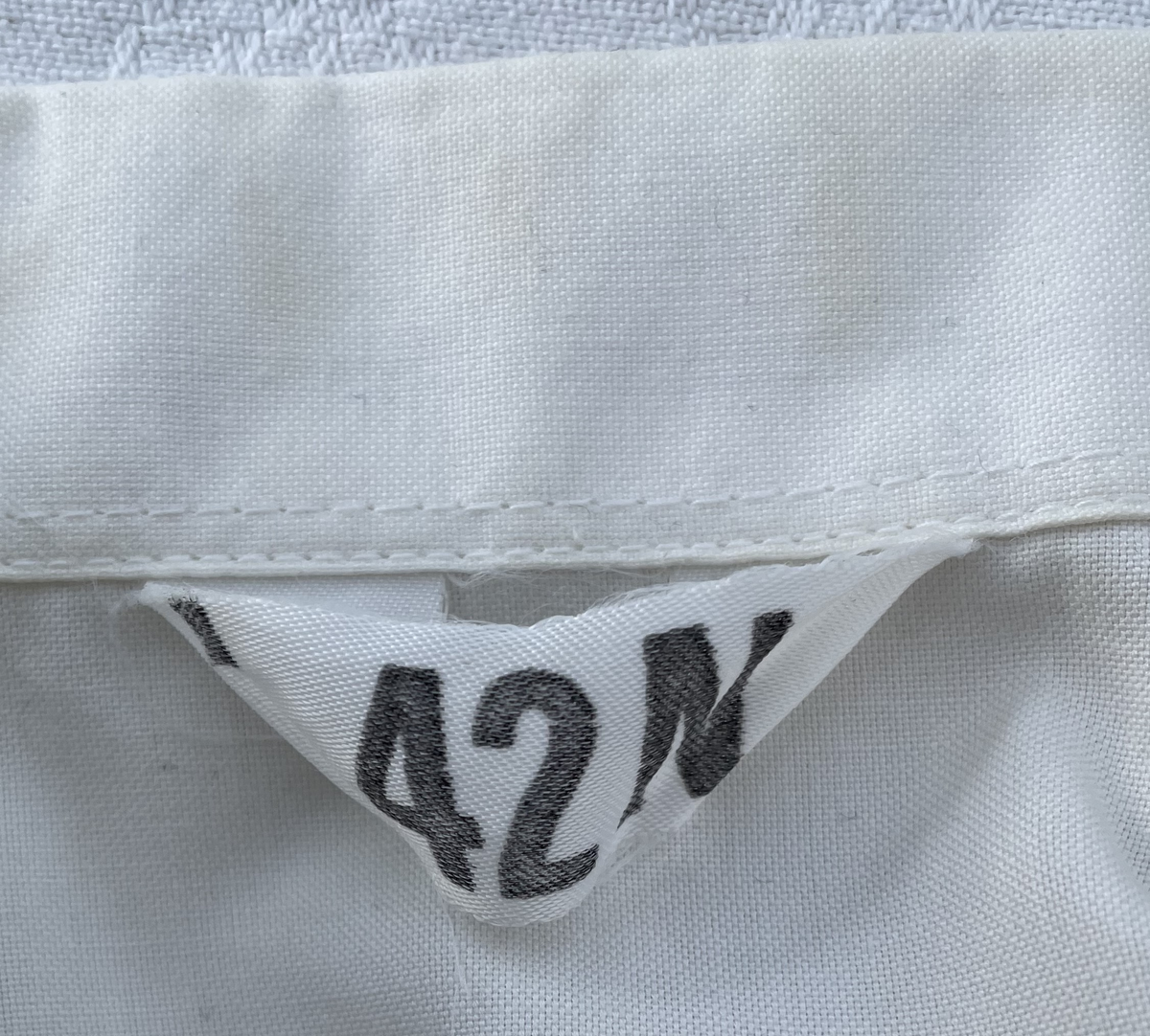 En vit skjortblus (Hemdbluse) för överstelöjtnant vid de östtyska gränstrupperna (Grenztruppen der DDR). Storlek 42N. Skjortblusen ingick i stabsuniform sommar (Stabsdienstuniform Nr. 2 So) och bars utan skjorta under.
Över höger bröstficka sitter en minnesmedalj för östtyska armens (Nationalen Volksarmee – NVA) 30-års jubileum. På nålfästet texten ”1956-1986”, på medaljens framsida ”30 JAHRE NATIONALE VOLKSARMEE” och på frånsidan ”Fest verwurzelt im Volk, gefürt von der Partei, erfüllen wir den Klassenauftrag. Forwärts zom XI. Parteitag der SEDI”.
Över vänster bröstficka sitter släpspännen. 
I övre raden band för (från höger till vänster från betraktarens håll); Vapenbrödramedaljen (Medaille der Waffenbrüderschaft) i brons och östtyska armens förtjänstmedalj (Verdienstmedaille der Nationalen Volksarmee) i brons, silver och guld.
I undre raden band för (från höger till vänster från betraktarens håll); medaljen för trogen tjänst i östtyska gränstrupperna (Medaille für treue Dienste in den Grenztruppen der DDR) 5 års tjänst, 10 års tjänst, 15 års tjänst och 20 års tjänst.