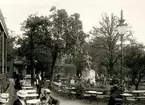 Gäster utanför schweizeriet Gubbhyllan vid Hasselbacken. Bellmanstatyn, som avtäcktes 1872, syns även till i bild.