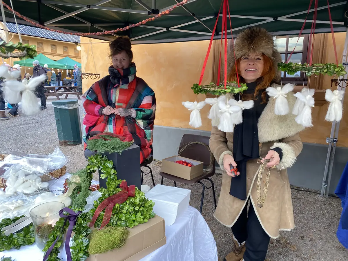 To kvinner selger julekranser på julemarkedet. 