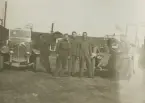 Gruppbild av militärer bredvid militärregistrerade bilar på Flygkompaniet på Malmen, omkring 1919-1920. Fem män och en hund.