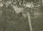 En militär bil tillhörande Flygkompaniet på Malmen har kraschat in i buskage, omkring 1919-1920. Två män står bredvid.